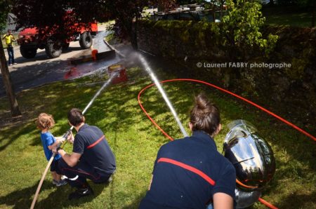 Photographe événementiel pour un centre de secours en Savoie : les apeurs pompiers montrent aux enfants comment tenir la lance à incendie