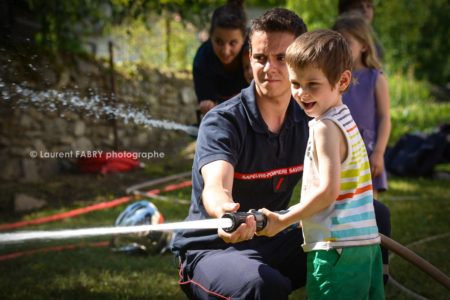 Photographe événementiel pour un centre de secours en Savoie : les enfants découvrent le maniement de la lance à incendie