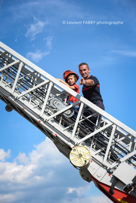 Photographe événementiel pour un centre de secours en Savoie : les enfants découvrent la grande échelle des pompiers