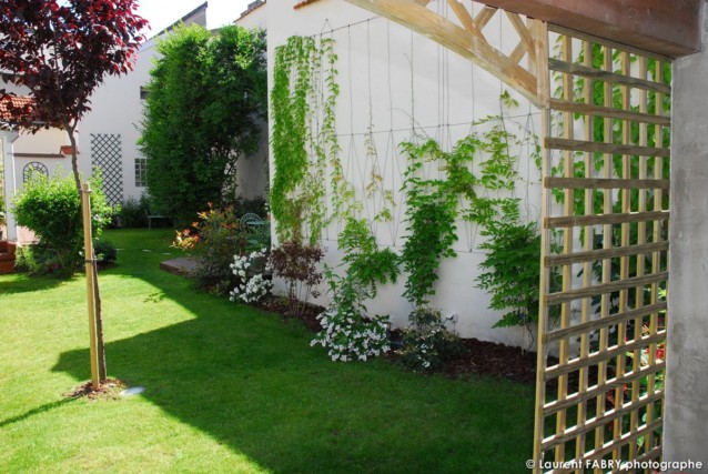 Photographe architecte paysagiste : un claustra en bois sépare l'abri ds voitures et le reste du jardin