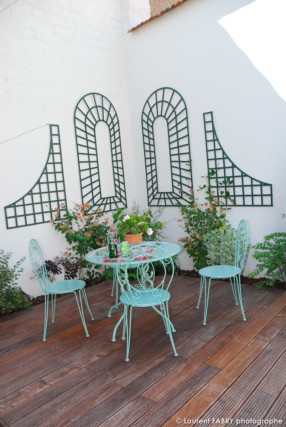 Photographe architecte paysagiste : petite terrasse en bois dans l'angle du jardin formé par les murs des voisins