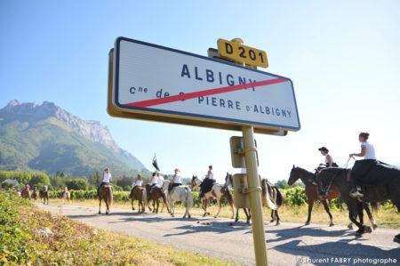 une équipe de cavaliers remonte la route depuis Albigny lors du rallye équestre, face à la dent d'Arclusaz