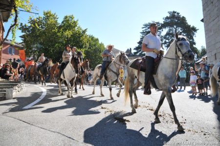 les cavaliers défilent sur la place de l'église devant les passant et le photographe de tourisme équestre à Saint-Pierre d'Albiny
