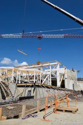 photographe de chantier à Aix-les-bains : vue verticale montrant les fondations, le chantier et son ossature bois, ainsi qu'une grue et le bras d'un engin de levage