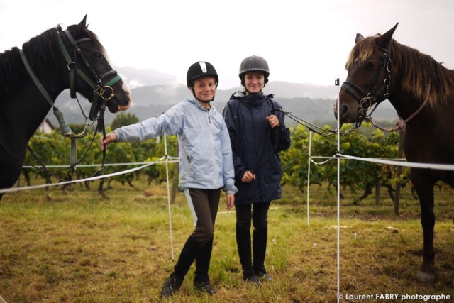deux jeunes cavalières posent devant le photographe de tourisme équestre près de leur cheval avant le rallye