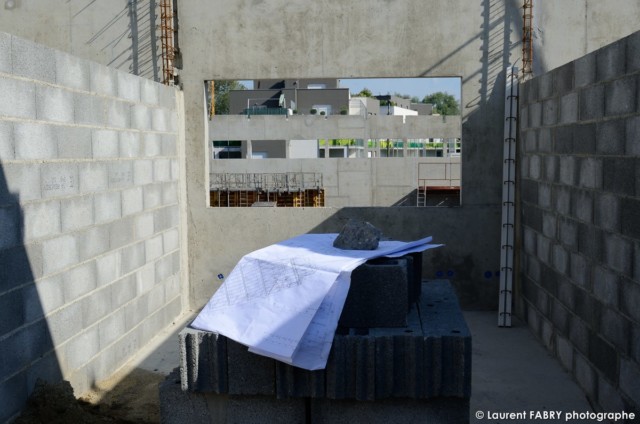 photographe de chantier à Aix-les-bains : dans une des futures pièces du bâtiment, un plan est posé sur un empilement de parpaings