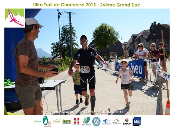 Photographe de trail en Chartreuse : un coureur arrive avec ses enfants et termine sa course avec un sourire sur le trail du grand duc de Charteuse