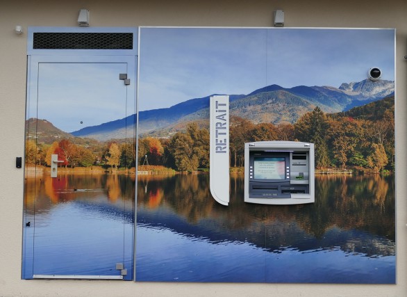 le distributeur automatique d'une agence bancaire décoré par une photo d'un lac en Combe de Savoie