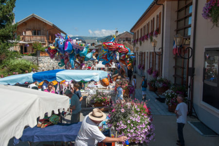 Photographe tourisme sur une fête de village en Savoie : exposants, producteurs et artisans dans la rue principale des Allues, face à la mairie
