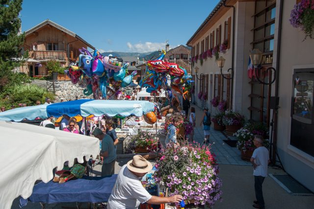 Photographe tourisme sur une fête de village en Savoie : exposants, producteurs et artisans dans la rue principale des Allues, face à la mairie