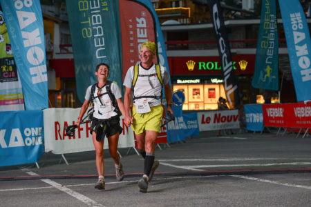 Photographe de trail running en Suisse : un couple termine sa course TVSB main dans la main, de nuit