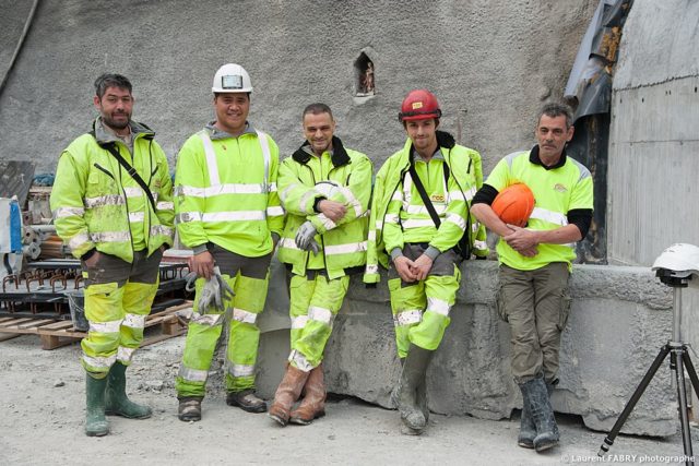 photographe industriel en Auvergne Rhône Alpes : les ouvriers du chantier posent à l'entrée du tunnel devant la Sainte Barbe