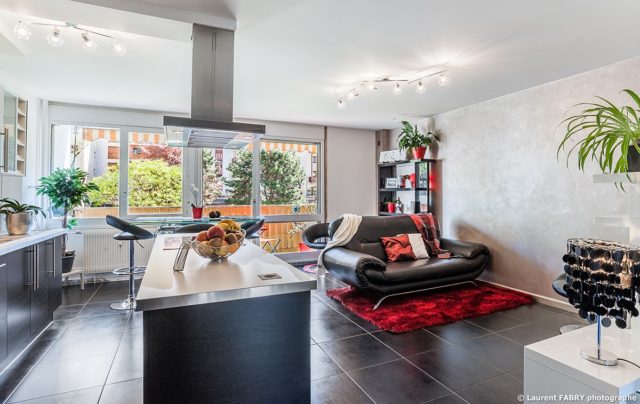 Photographe immobilier pour un appartement à Chambéry : vue générale de la pièce de vie et ses baies vitrées