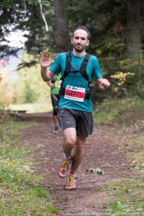 Un coureur de trail fait un signe de la main au passage devant le photographe