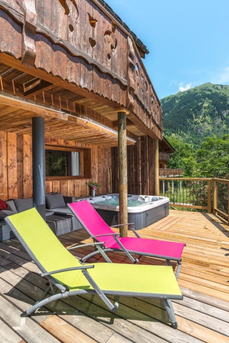 Coin détente avec jacuzzi extérieur sur la terrasse du chalet