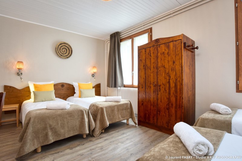 chambre avec plusieurs lits et grande armoire en bois