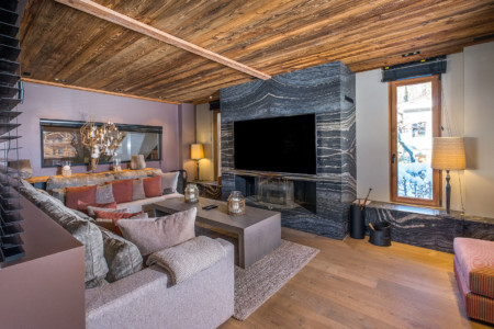 Photographe chalet à Megève : Coin TV avec sa cheminée en marbre dans un chalet de luxe à Megève