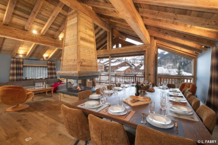 Chalet Kalinka : pièce de vie avec table dressée et cheminée allumée