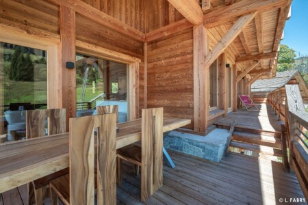 Chalet de luxe dans le Val d'Arly : large balcon accueillant une table et des chaises en bois passif
