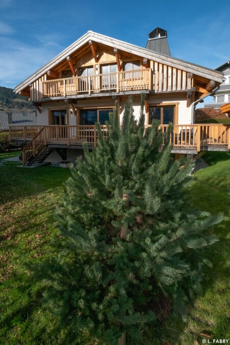Chalet de luxe photographié à Megève : vue extérieure sur le petit parc arboré
