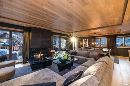 Chalet de luxe photographié à Megève : en pièce principale, grand salon salle à manger accueillant la lumière du soir