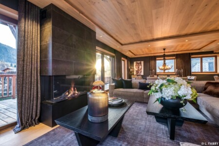 Chalet de luxe photographié à Megève : en pièce principale, grand salon salle à manger accueillant la lumière du soir